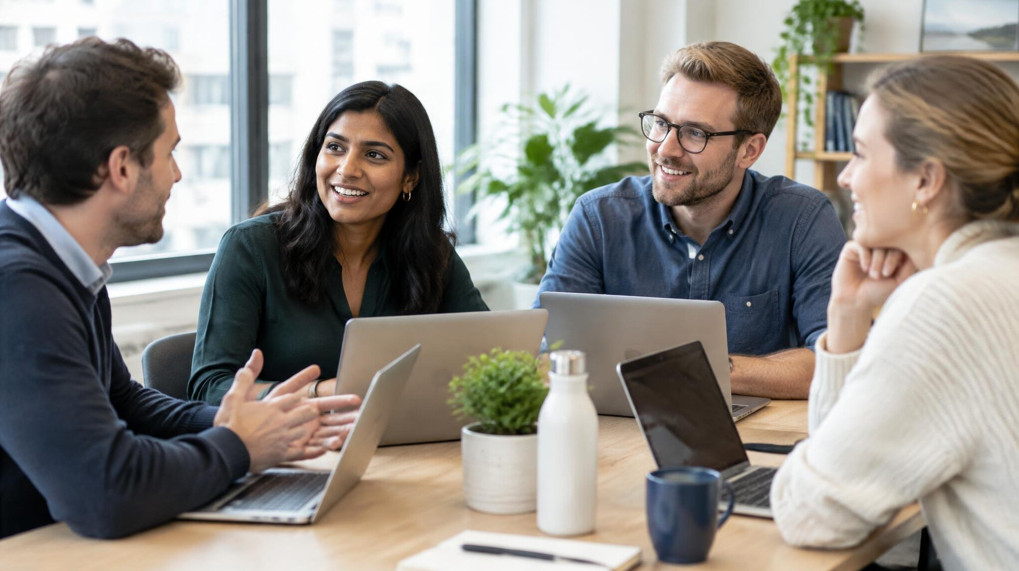 Colleagues talking around a table with laptops